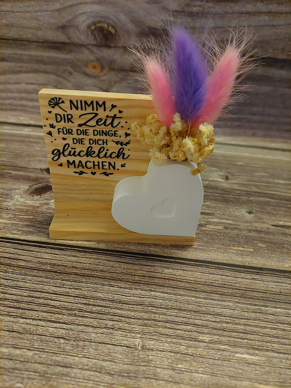 kleine Förmchen mit Trockenblumen und Holzscheibe oder Holzhintergrund