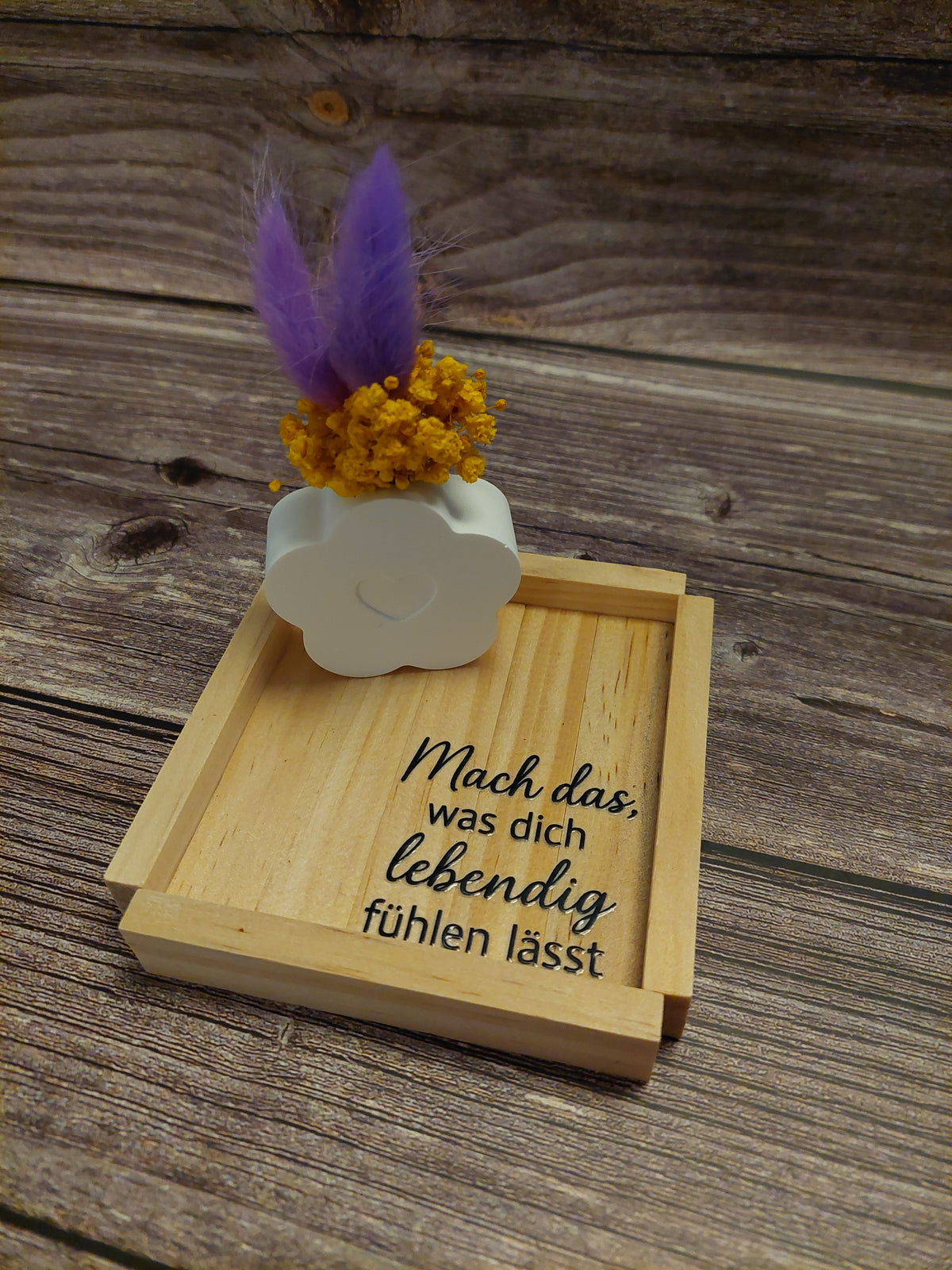kleine Förmchen mit Trockenblumen und Holzscheibe oder Holzhintergrund