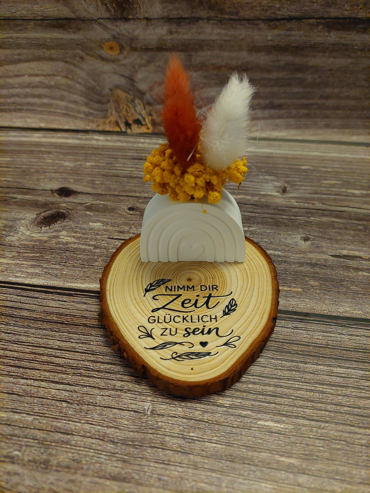 kleine Förmchen mit Trockenblumen und Holzscheibe oder Holzhintergrund
